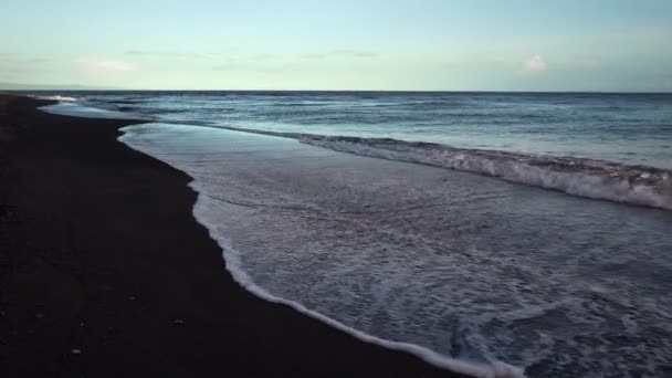 Ondas de espuma blanca en la playa con arena volcánica negra en clima tormentoso — Vídeo de stock