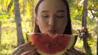Çekici, tatlı, esmer, karpuz yiyen genç bir kadının yakın çekimi..