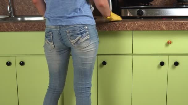 Genç bir kadın mutfağı yıkıyor ve dans ediyor. Eğlenceli ev temizliği. — Stok video