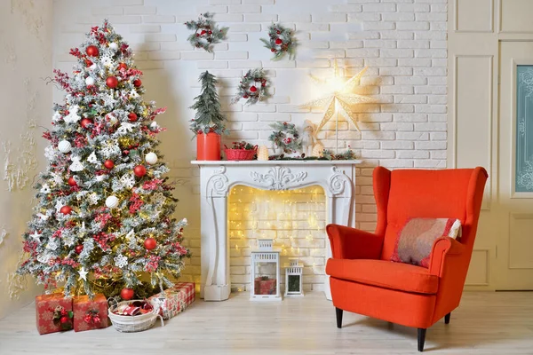 Oturma odasında Noel süsleri, kırmızı koltuklar, Noel ağacı ve çelenkler.