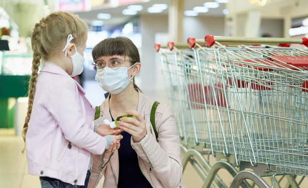 お母さんとともに小さな娘apply sanitizer gelでザ · モール身に着けている顔マスク — ストック写真