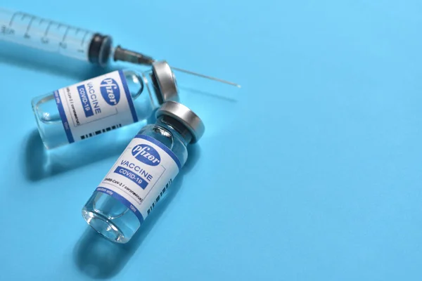 STARIY OSKOL, RUSIA - 23 de noviembre de 2020: Concepto de vacuna contra el coronavirus Pfizer y jeringa sobre fondo azul con espacio para copiar —  Fotos de Stock