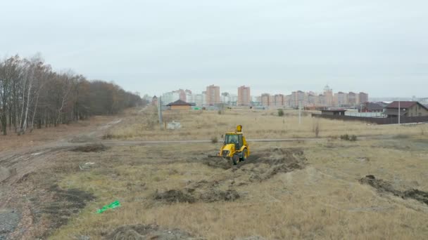 STARIY OSKOL, RUSSIA - DECEMBER 2, 2020: Aerial view of backhoe loader leveling landscape for residential construction — Stock Video