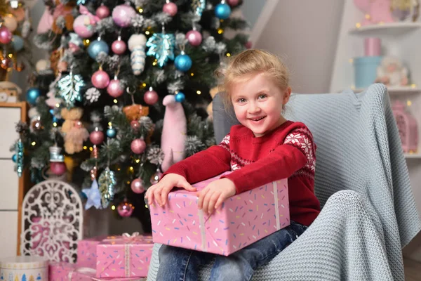 Усміхнена дівчинка тримає різдвяний подарунок у подарунковій коробці — стокове фото
