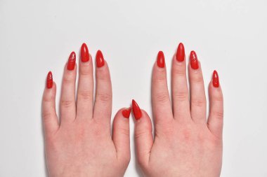 Yeniden uzamış kırmızı jel tırnaklı kadın elleri.