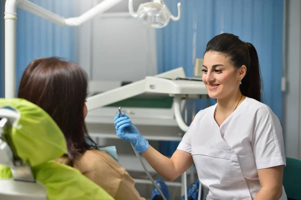 Mulher dentista sorrindo enquanto trabalhava com paciente — Fotografia de Stock