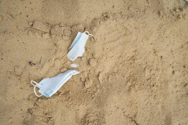 Jednorázová maska v písku na pláži, koncepce karantény a dovolené na moři — Stock fotografie
