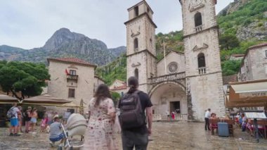 KOTOR, MONTENEGRO - 18 Temmuz 2021: Kotor 'daki eski kasabada turistlerin zaman aşımına uğraması, tarihi eser olan St. Tryphon kilisesine bakmaları,