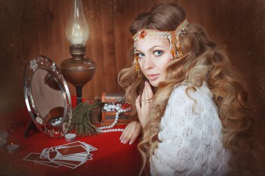Genç güzel kız fortune teller masa bir lamba ile oturuyor.