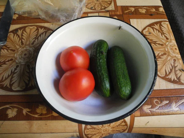 tomatoes and cucumber in the bowl on the table.
