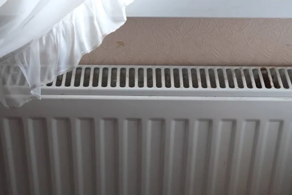 Bir adamın eli, bir apartman dairesinde ve soğuk bir evde soğuk radyatörlere tutunuyor.