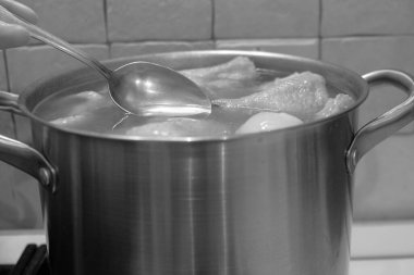 Metal bir tencerede kaşıkla kaynayan bir suyun yakın plan çekimi.