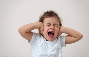 Parlak bir geçmişi olan küçük bir kız gözlerini ve kulaklarını kapatarak çığlık atıyor..