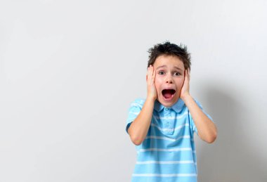 Mavi tişörtlü çocuk ellerini başının arkasında tutuyor ve bağırıyor..