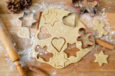 Durgun bir hayat, yuvarlanmış hamurlu mutfak masası, çiğ zencefilli kurabiye hazırlıkları ve tarçın çubukları. Ladin konilerinin tepesinde.