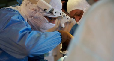 Cerrahi operasyon, hemşirenin omzunun arkasından görüş, baş cerrah sorumlu bir manipülasyon yapar. Odaklandı..