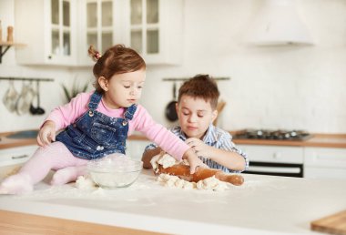 Kız merdaneye uzanır, oğlan hamuru yoğurur.