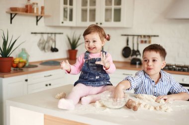 Çocuklar gülümser ve un içinde ellerini gösterir.