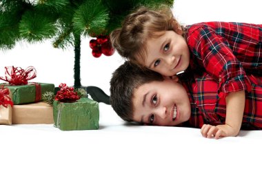 Beyaz üzerine izole edilmiş bir portre. Küçük kız kardeşi erkek kardeşinin üstünde yatıyor, çocuklar gülümsüyor. Kutuların yanında hediyeler var..