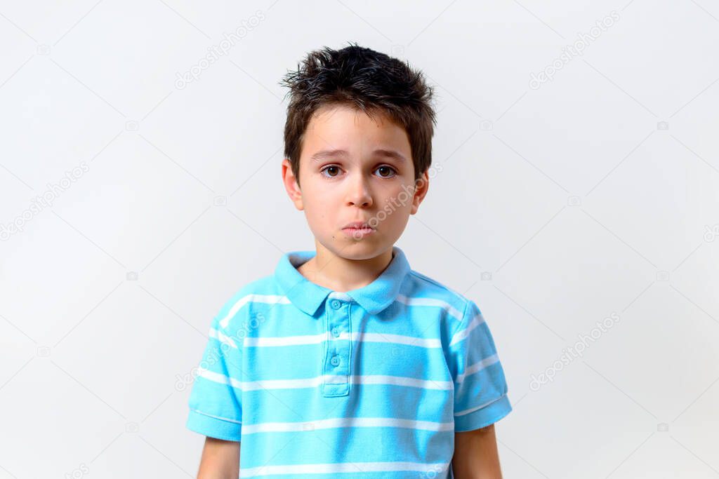 The boy in a blue T-shirt looks sadly and surprised at the camera.