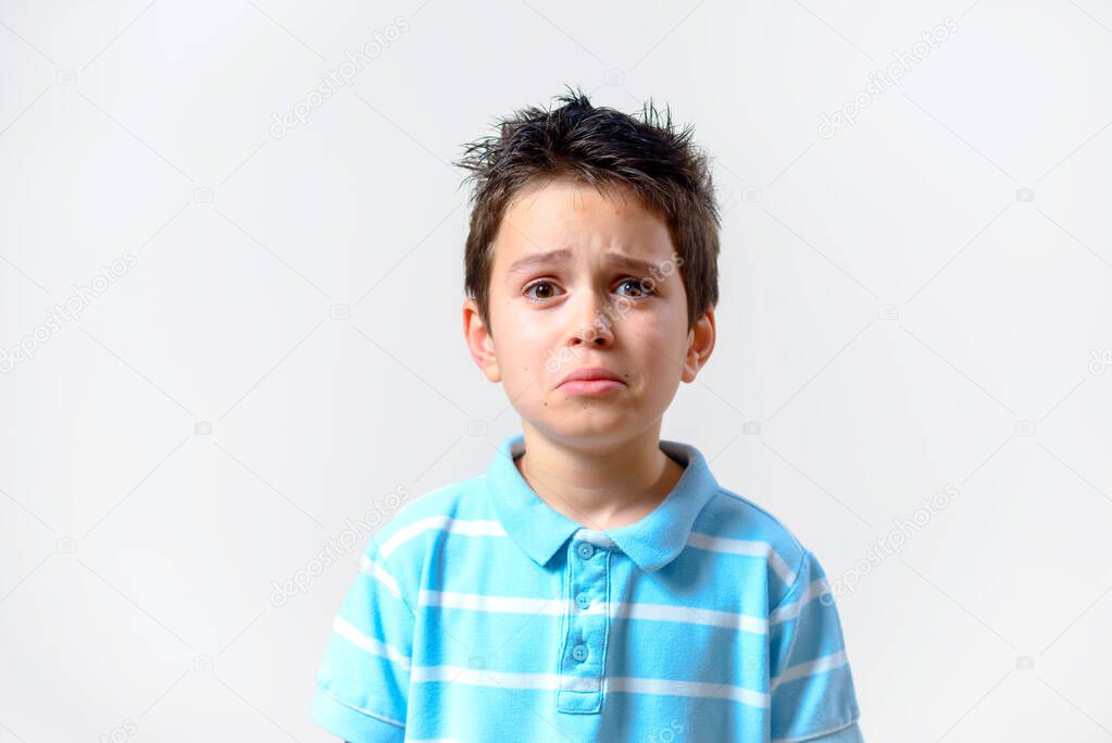 The boy in a blue T-shirt with a disgruntled expression looks squinted at the camera.