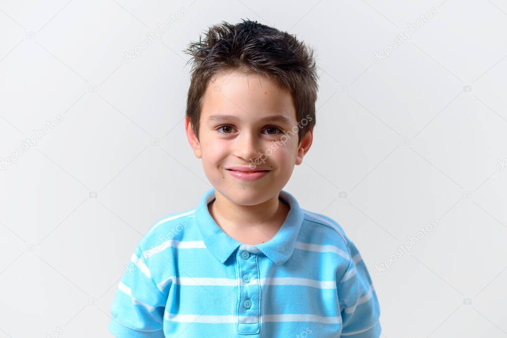 The boy in a blue T-shirt smiles looking into the camera.