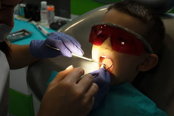 歯医者さんが歯医者さんの所で小さな男の子の歯を調べる — ストック写真