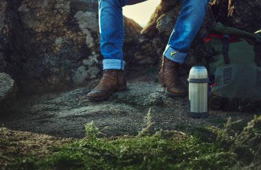 Metal bir termos, seyahat çantası, dik kayalıklarda eski kahverengi deri çizmeler..