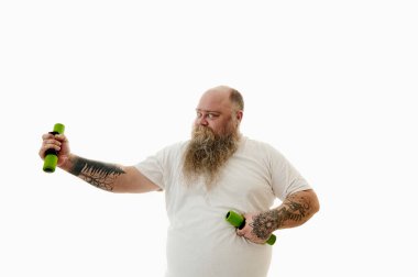 Bir adam bir dambılı uzanmış eliyle tutar ve sinsice bakar.