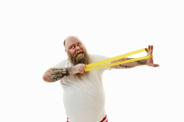 Obez sakallı bir adamın beyaz arka planında izole edilmiş bir portre. Kolları dövmeli ve jimnastik bandı takıyor.