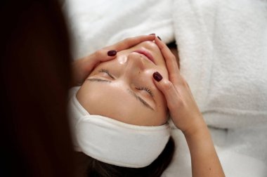 Rahatlatıcı bir yüz masajı sırasında rahatlamış spa müşterisinin yukarıdan görüntüsü