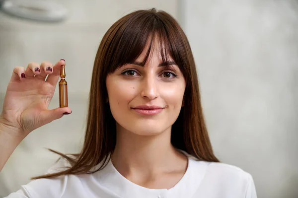 Eine Schöne Frau Hält Eine Ampulle Aus Dunklem Glas Auf — Stockfoto