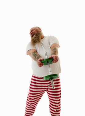 Demir bir dambıl uzatan sakallı şişman bir adam. Beyaz bir arka planda dövmeli kilolu bir adamın izole edilmiş portresi.