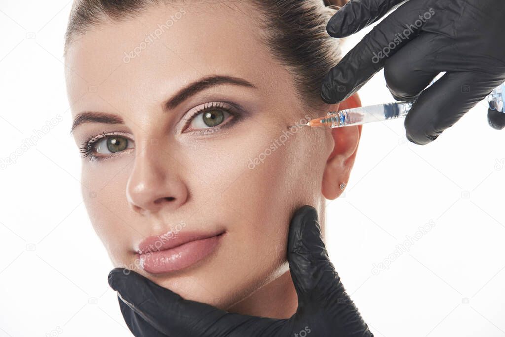 Young woman receiving cosmetic anti aging treatment with syringe injection.
