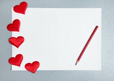 Düz beyaz kağıt, kırmızı kalem ve gri arka plana kalp serpiştirilmiş. Sevgililer Günü konsepti.