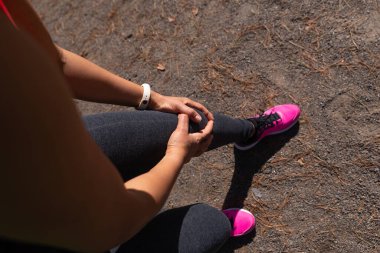 Sporcu kadın koşudan sonra elleriyle dizini sıktı ve acı hissetti..