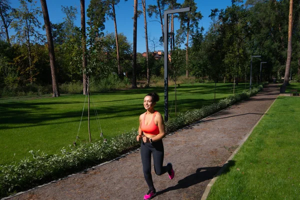 The young woman in sportswear runs in the park. Outdoor sports.