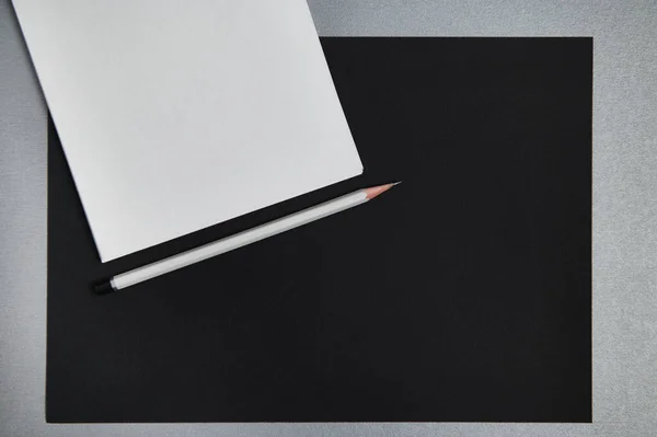 Sheets of paper and gray wooden pencil. Black and white still life. Flat lay . Top view.