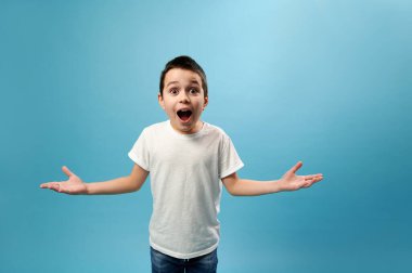 Şok olmuş çocuk kamerada şaşkınlığını dile getiriyor. Mavi arkaplanda kopyalama alanı olan yüz duyguları