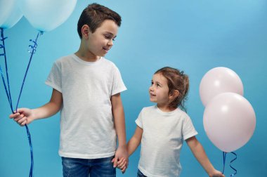 Bir erkek ve bir kız yan yana durur, el ele tutuşur ve şefkatle birbirlerine bakarlar. Mutlu bir çocukluk. Çocuk koruma günü