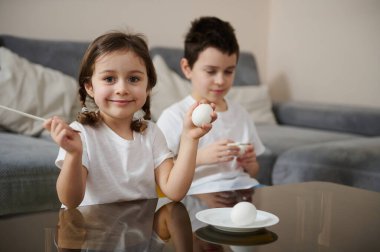 Yumurta, fırça ve paskalya yumurtası tutan iki sevimli çocuk. Paskalya konsepti