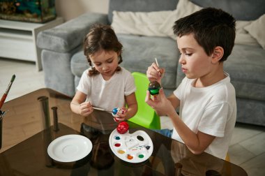 Masada oturan güzel çocuklar, Paskalya için yumurtaları renkli boyalarla süslemeye odaklanmışlar. Geleneksel olay - Paskalya