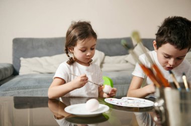Paskalya yumurtalarını renkli boyalarla süsleyen iki sevimli çocuk. Geleneksel Paskalya kutlaması kavramı