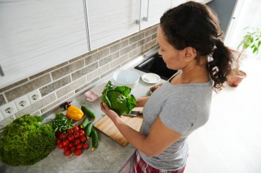 Güzel, ince, Afro-Amerikan kadın elinde yeşil bir marul tutarak sağlıklı salata hazırlıyor. Vejetaryen gıda konsepti