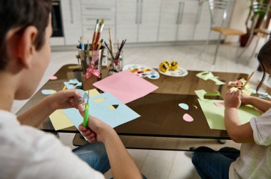 Evde okul ve anaokulu öğrencilerinin renkli kağıtlardan şekiller çizip kesmesi. Çocukların yaratıcılık kavramı