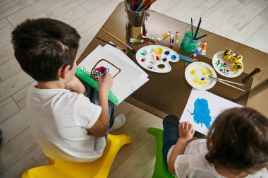 Çocuklar kağıda suluboya resimler çiziyor. Çocukların yaratıcılık konsepti. Yüksek açı görünümü