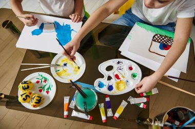 Çocukların elleri kağıda suluboya resimler çiziyor. Çocukların yaratıcılık konsepti. Yüksek açı görünümü