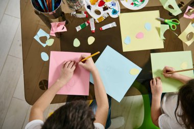 Renk kağıdından şekiller çizen ve kesen çocukların yüksek açılı görüntüsü. Düz yatıyordu