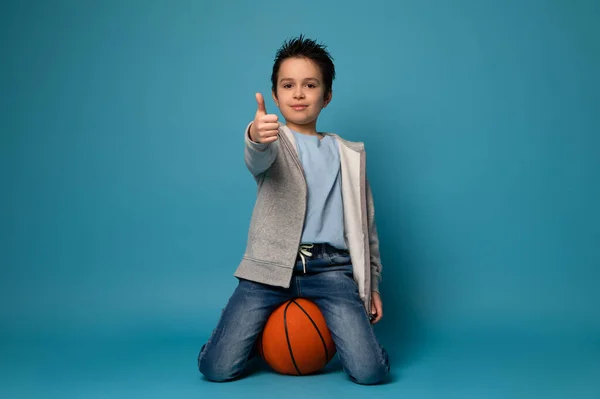 Joven Jugador Baloncesto Sentado Una Bola Naranja Mostrando Pulgar Hacia — Foto de Stock