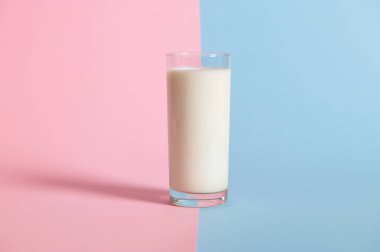 İki renkli pembe ve mavi arka planda pipetli taze sütlü bir bardak. Boşluğu kopyala